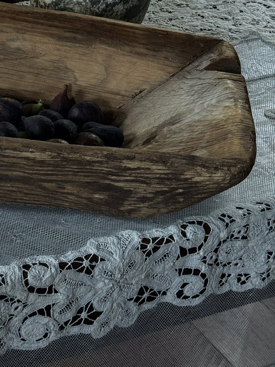 a Turkish dough bowl filled with figs sits on a lace table cloth