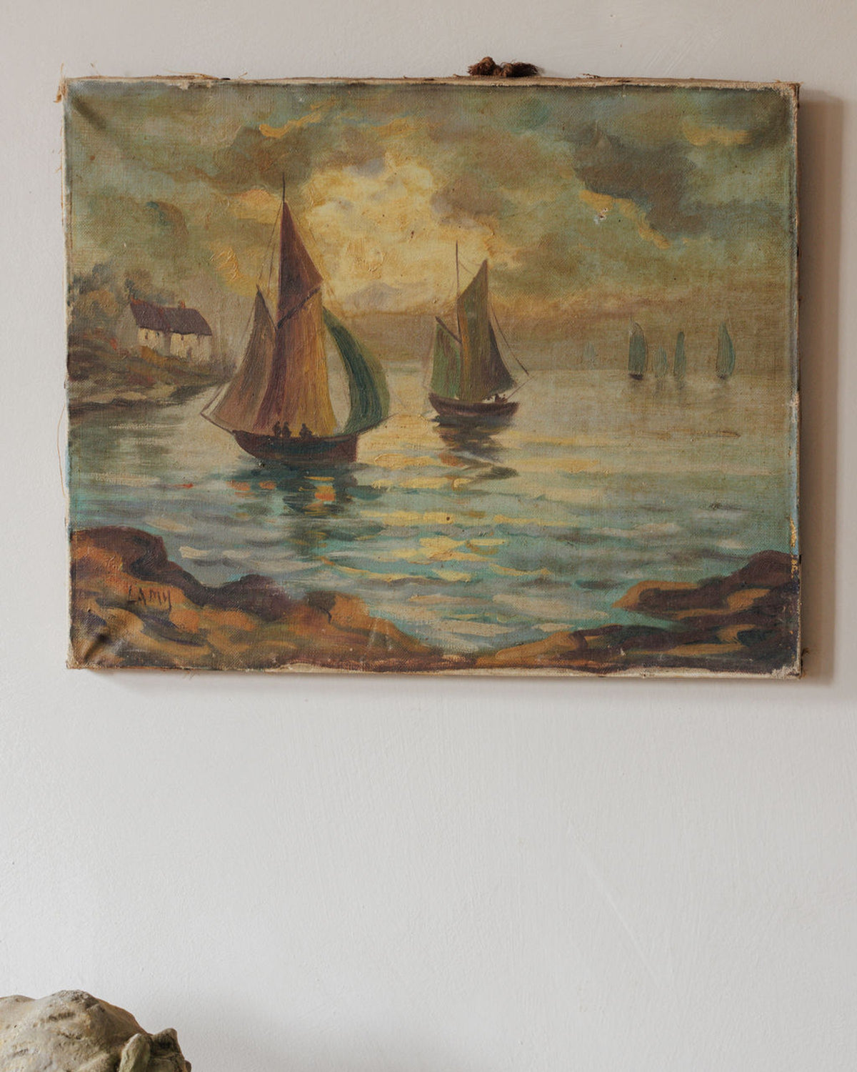 A vintage oil painting of a seaside village with sailboats on the water under a warm, cloudy sky, signed Lamy.