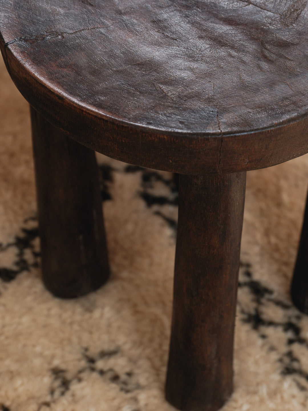 a close up of a wooden stool on a rug .