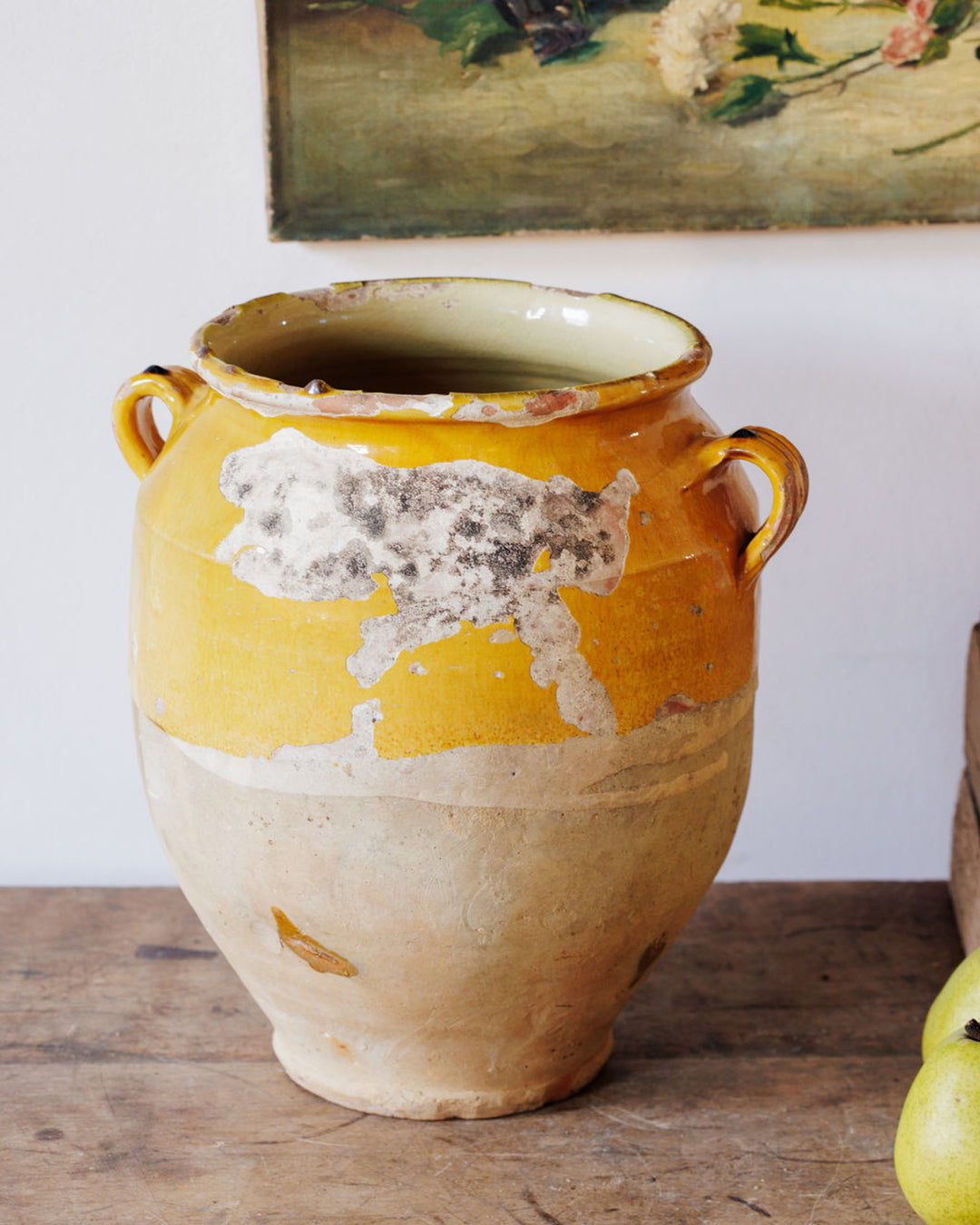 Distressed yellow and beige ceramic pot with two handles.