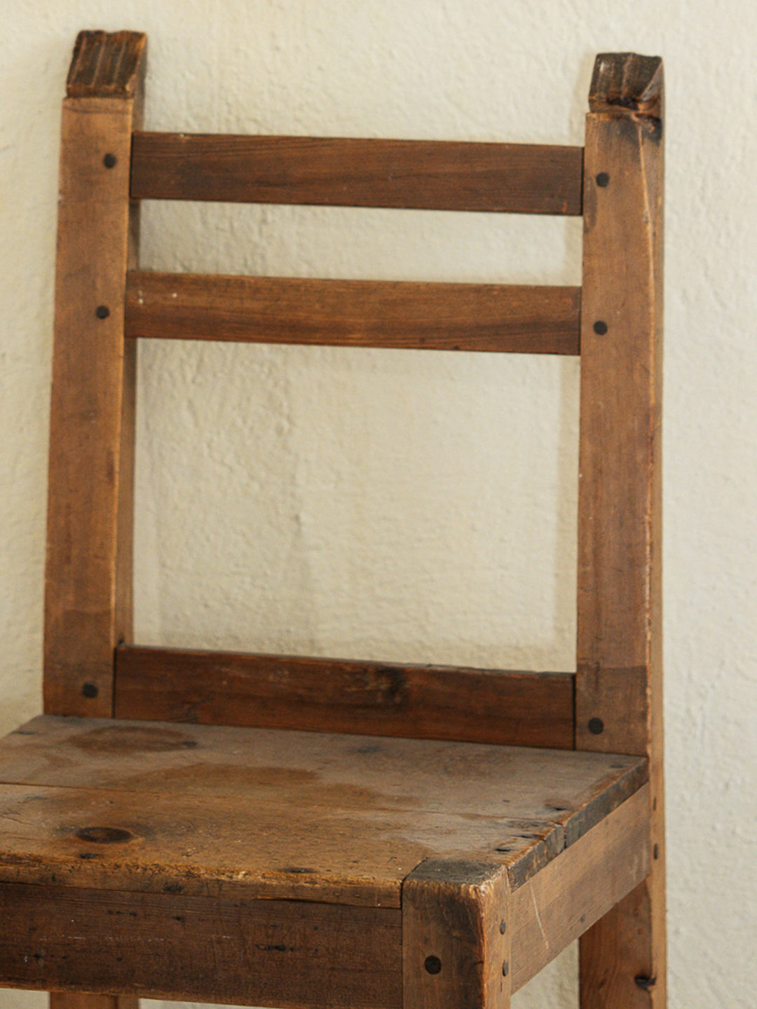 a wooden chair is against a white wall