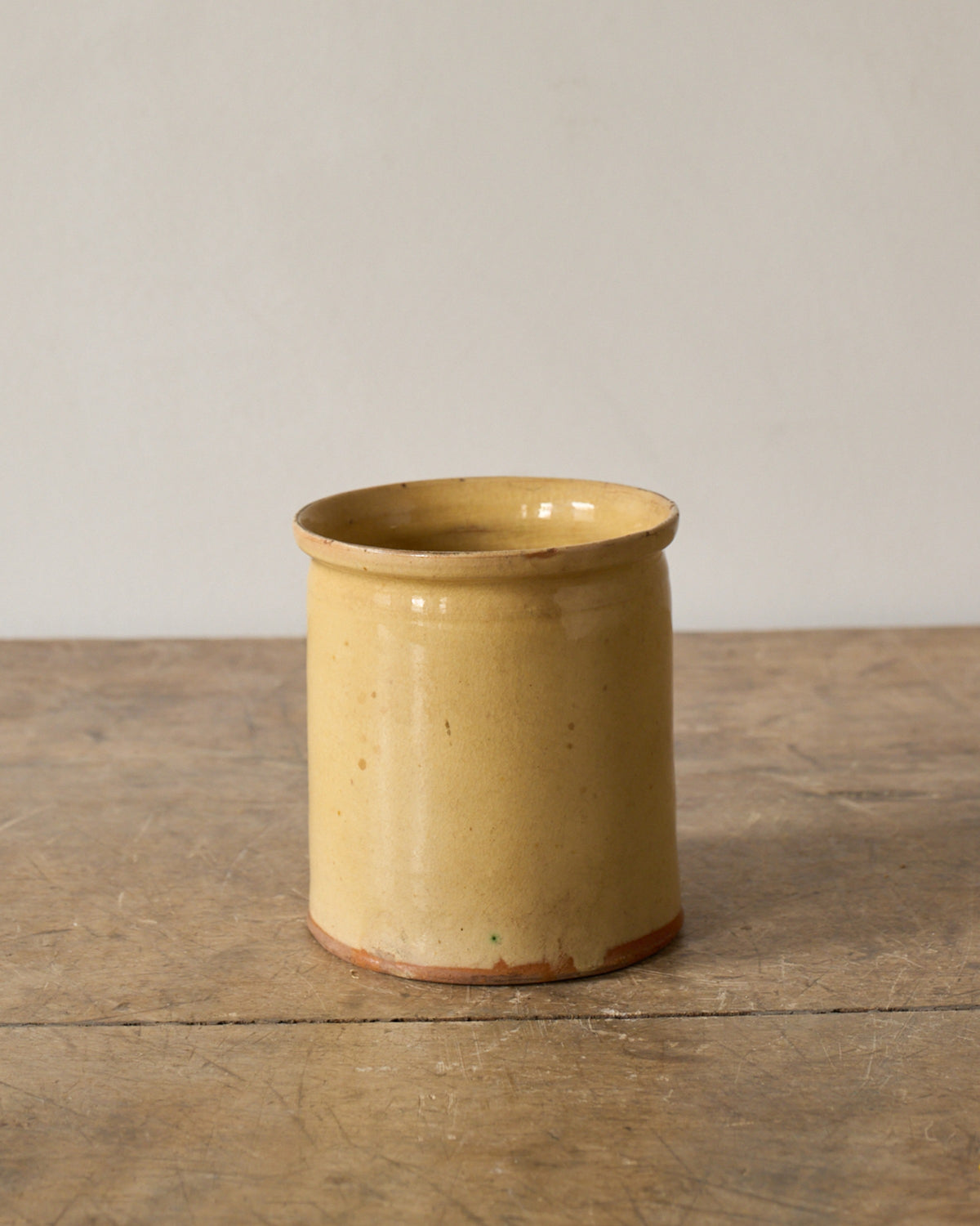 Vintage yellow glazed ceramic pot on a wooden surface.
