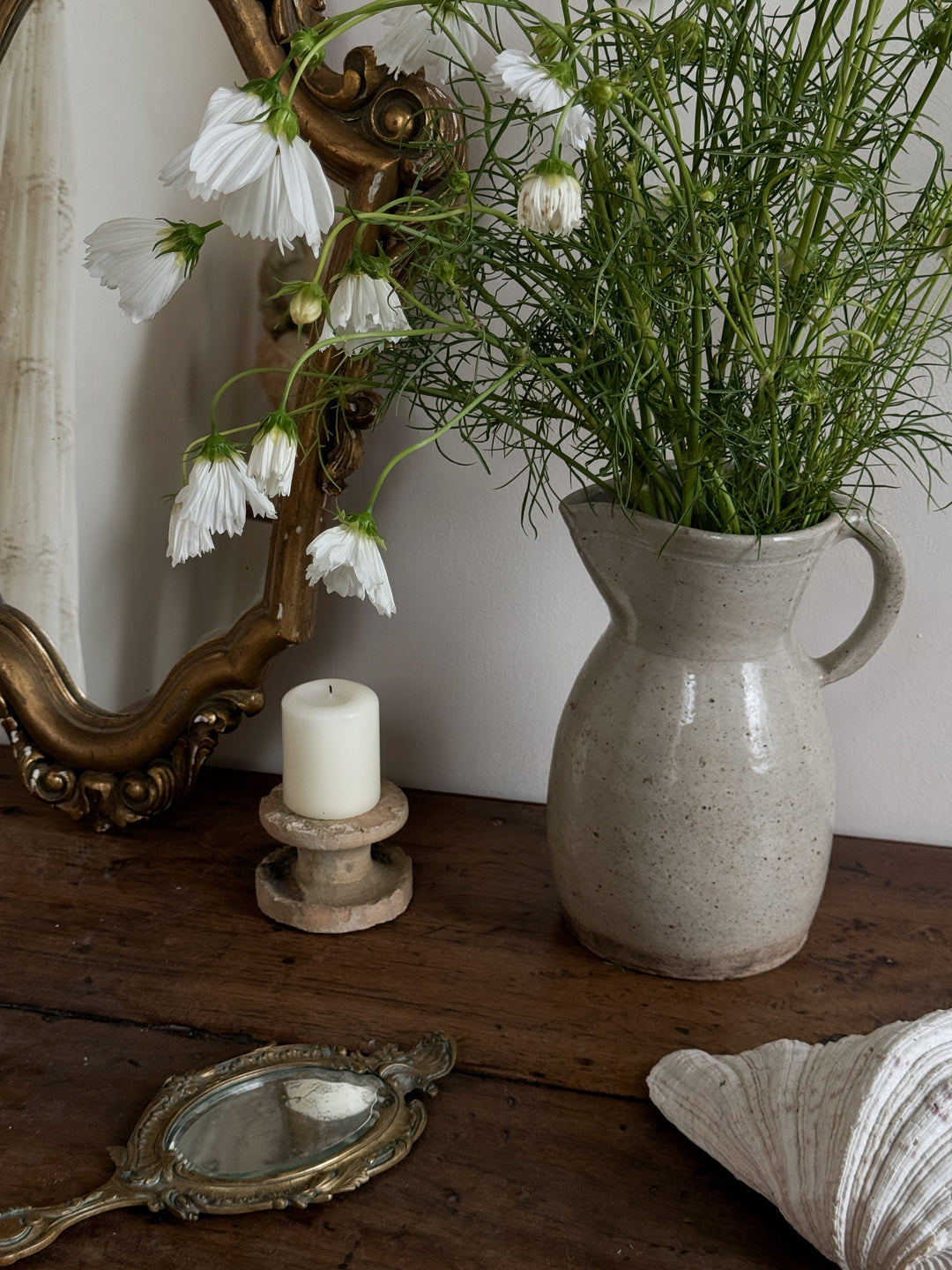 a vase of flowers sits on a table next to a mirror and a candle