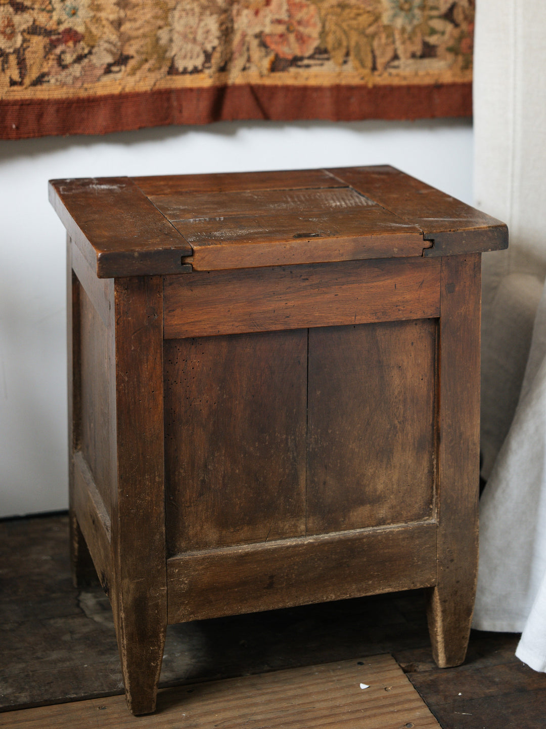 a small salt box is sitting on a wooden floor next to a wall .