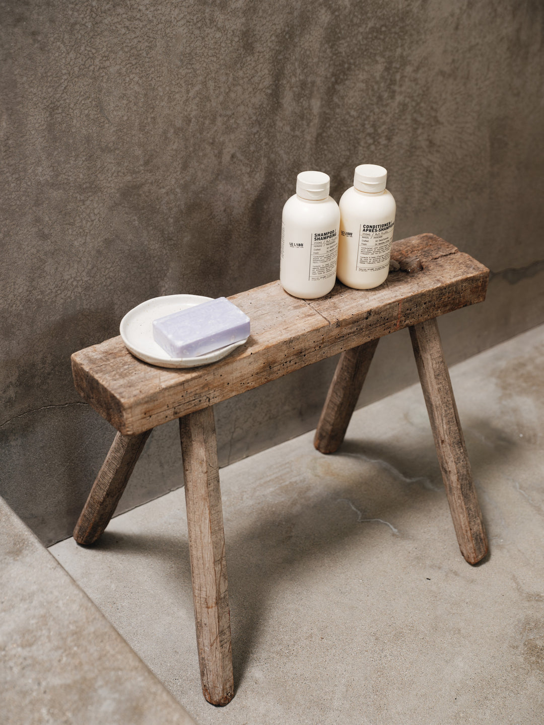 two bottles of conditioner sit on a wooden bench