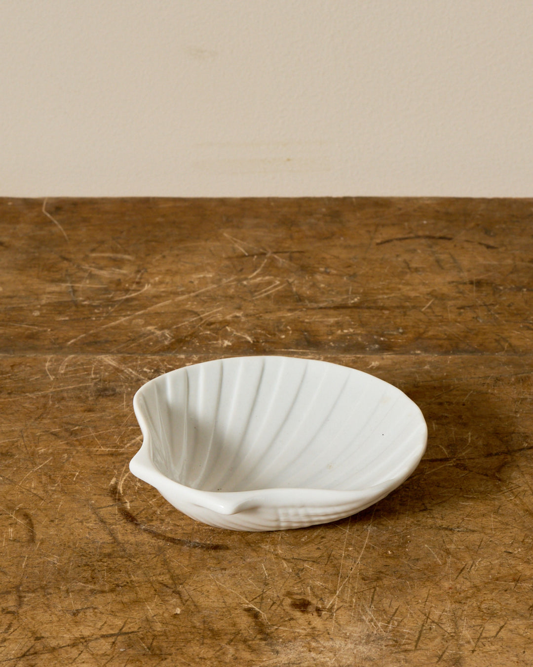 A white ceramic shell-shaped bowl on a wooden surface.