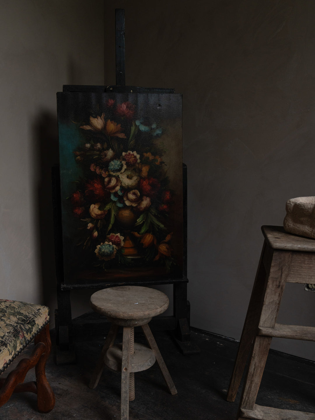 a painting of flowers is on an easel in a dark room