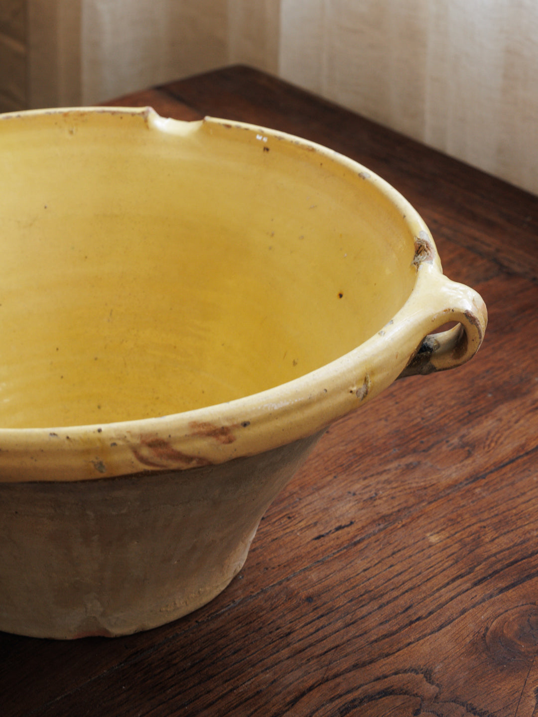 a yellow tian bowl is sitting on a wooden table
