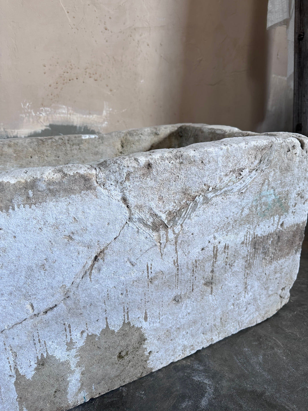 a large stone planter is sitting on a table next to a wall .