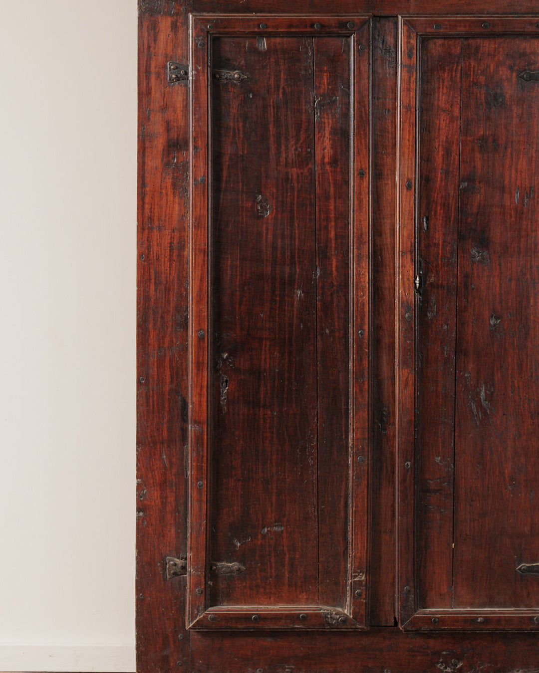 Aged dark reddish-brown wooden doors with recessed panels, visible grain, and small metal studs.