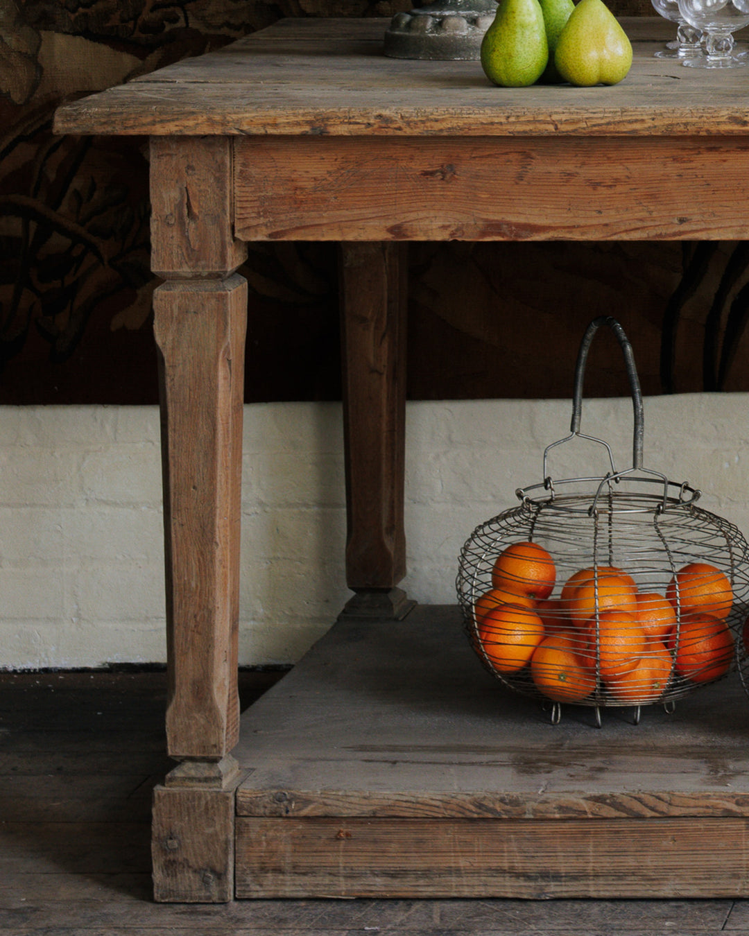 a basket of oranges sits on a wooden table