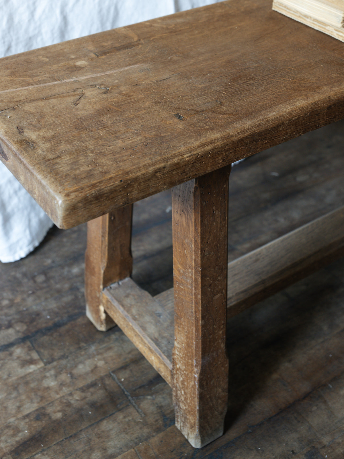 a french oak bench is sitting on a wooden floor