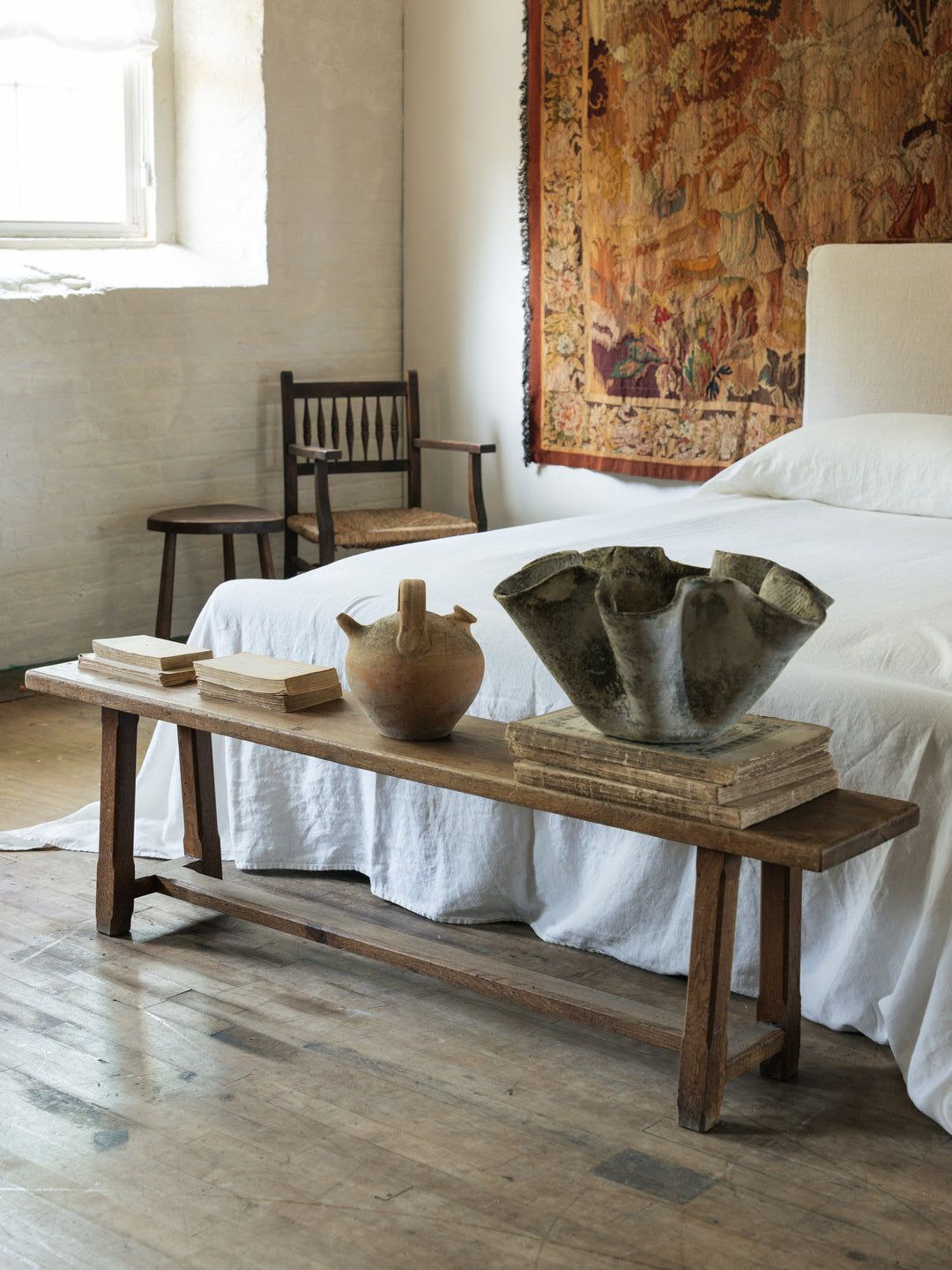 a wooden bench sits in front of a bed in a bedroom