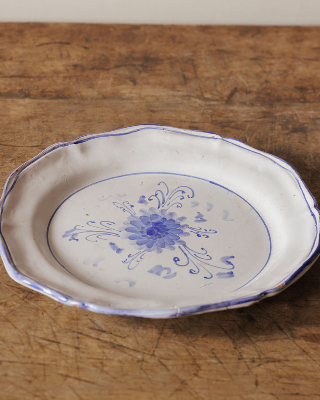 A white ceramic plate with a blue floral design and scalloped edge rests on a wooden table.
