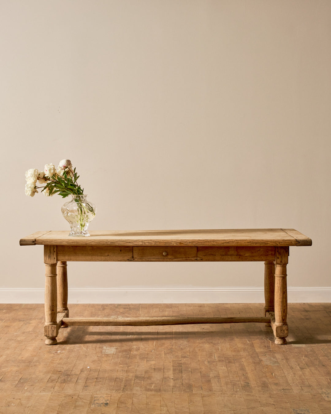 Rustic wooden table with a vase of white flowers.