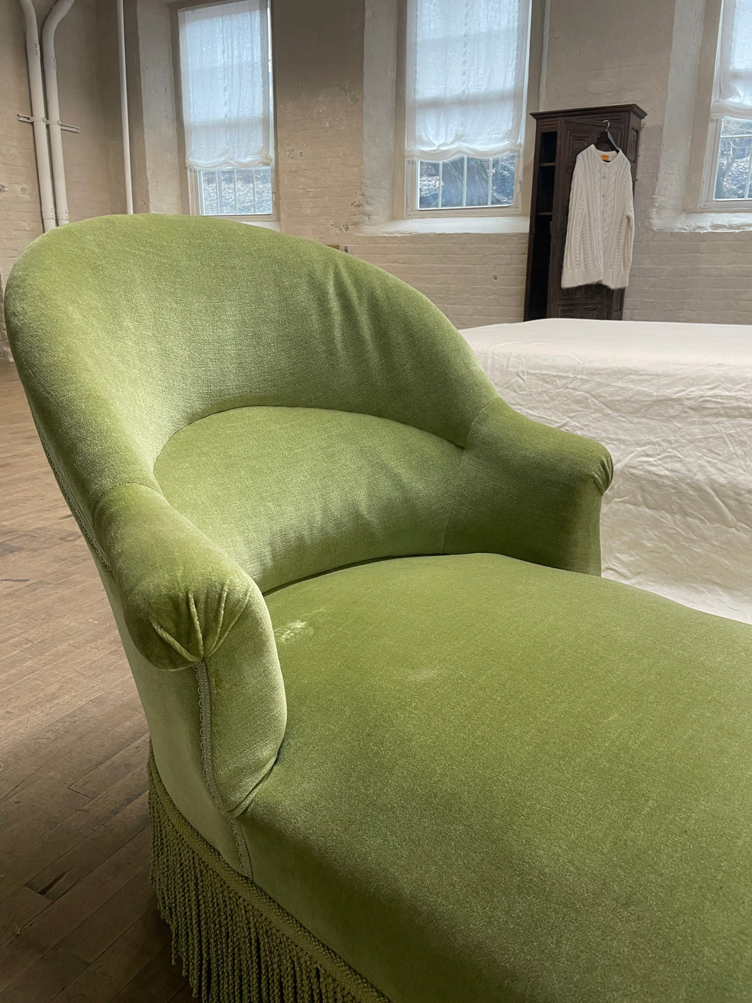 a green chair is sitting in a room next to a bed .