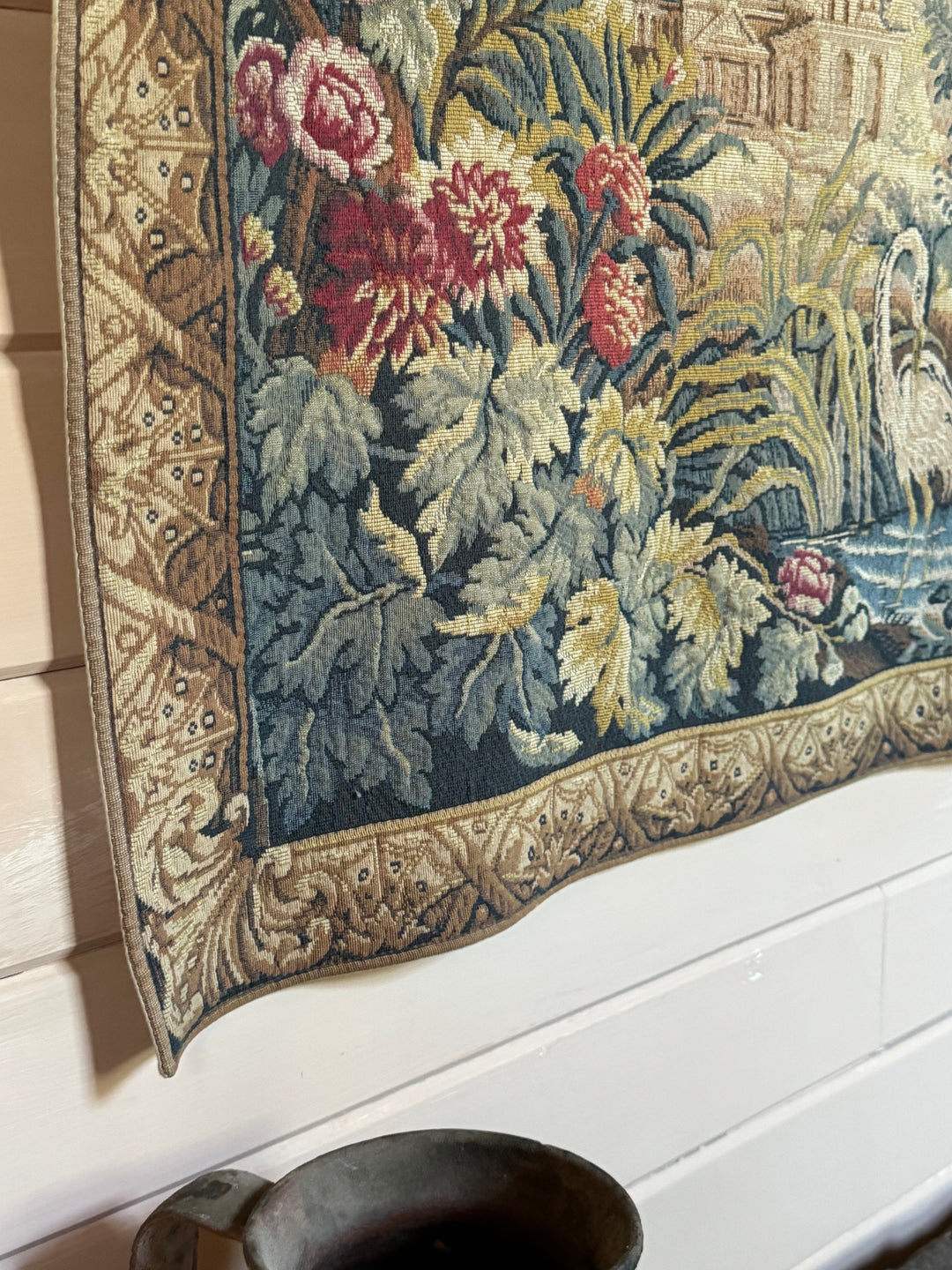 a floral tapestry is hanging on a wall next to a vase