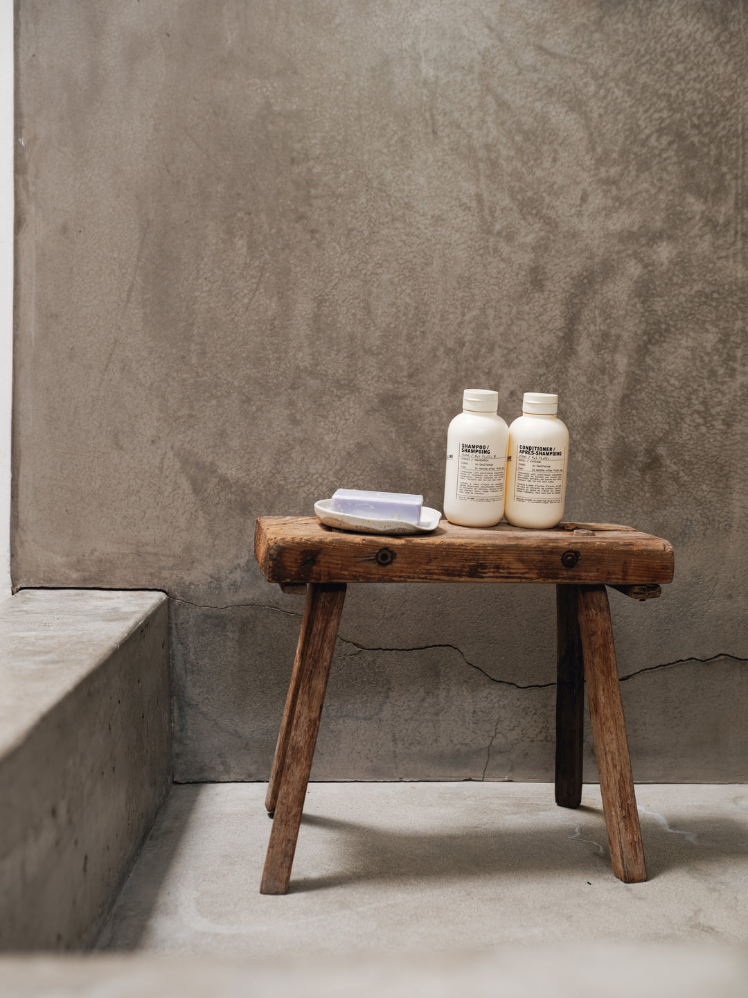 two bottles of conditioner sit on a wooden stool