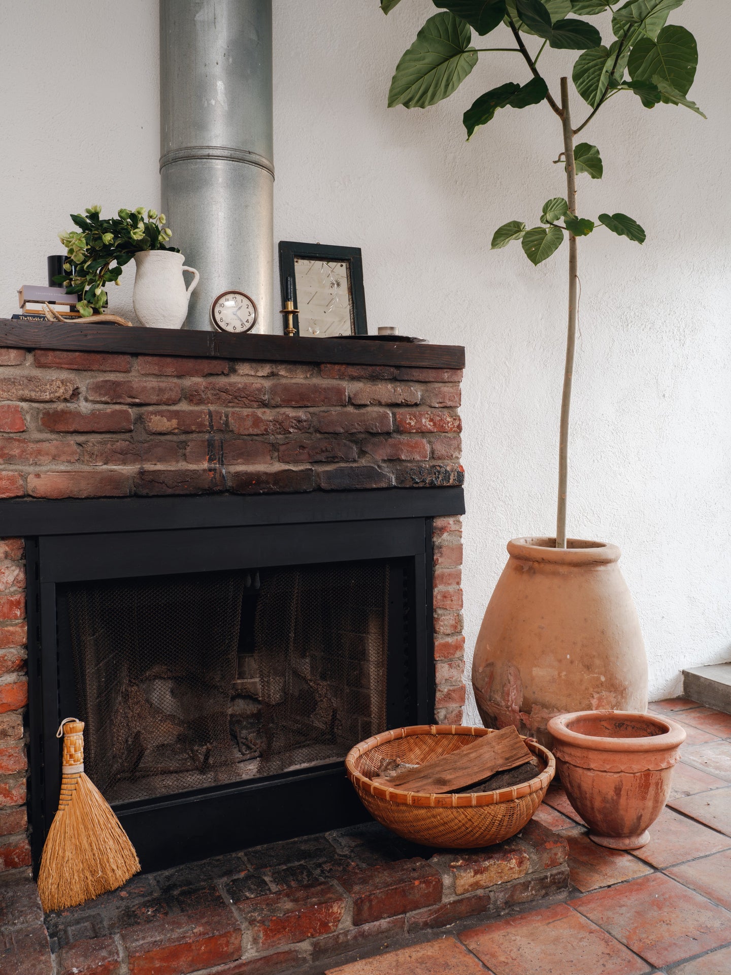 a fireplace with a broom and baskets in front of it