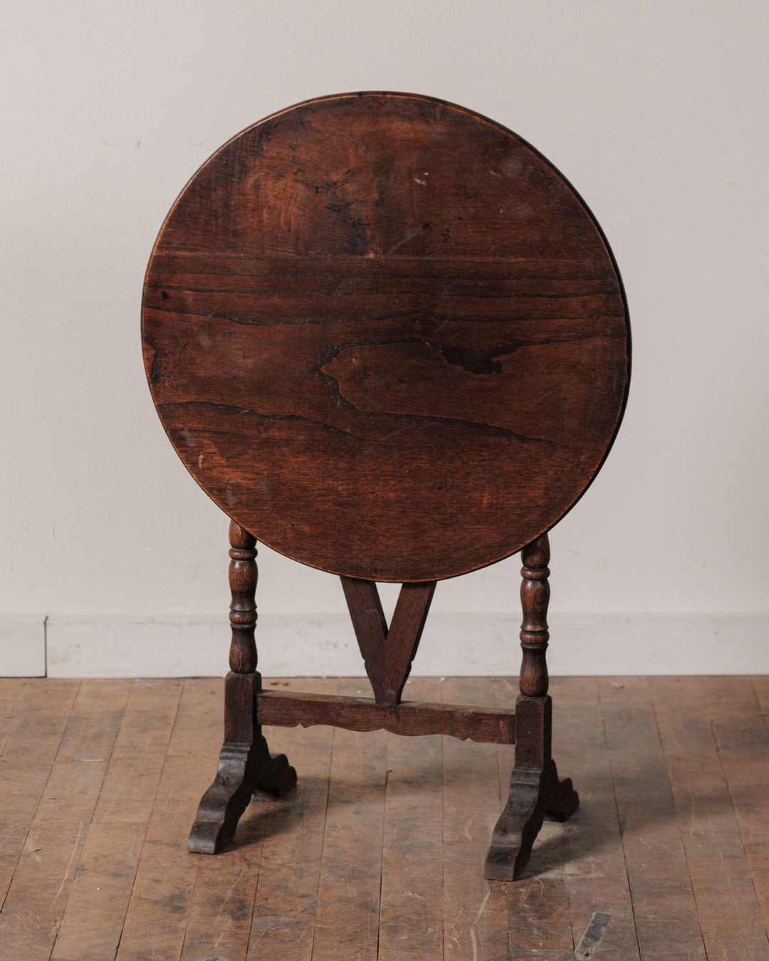 Antique wooden gateleg table with its round top folded vertically.