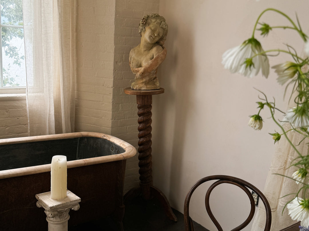 there is a statue of a woman on a pedestal next to a bathtub .