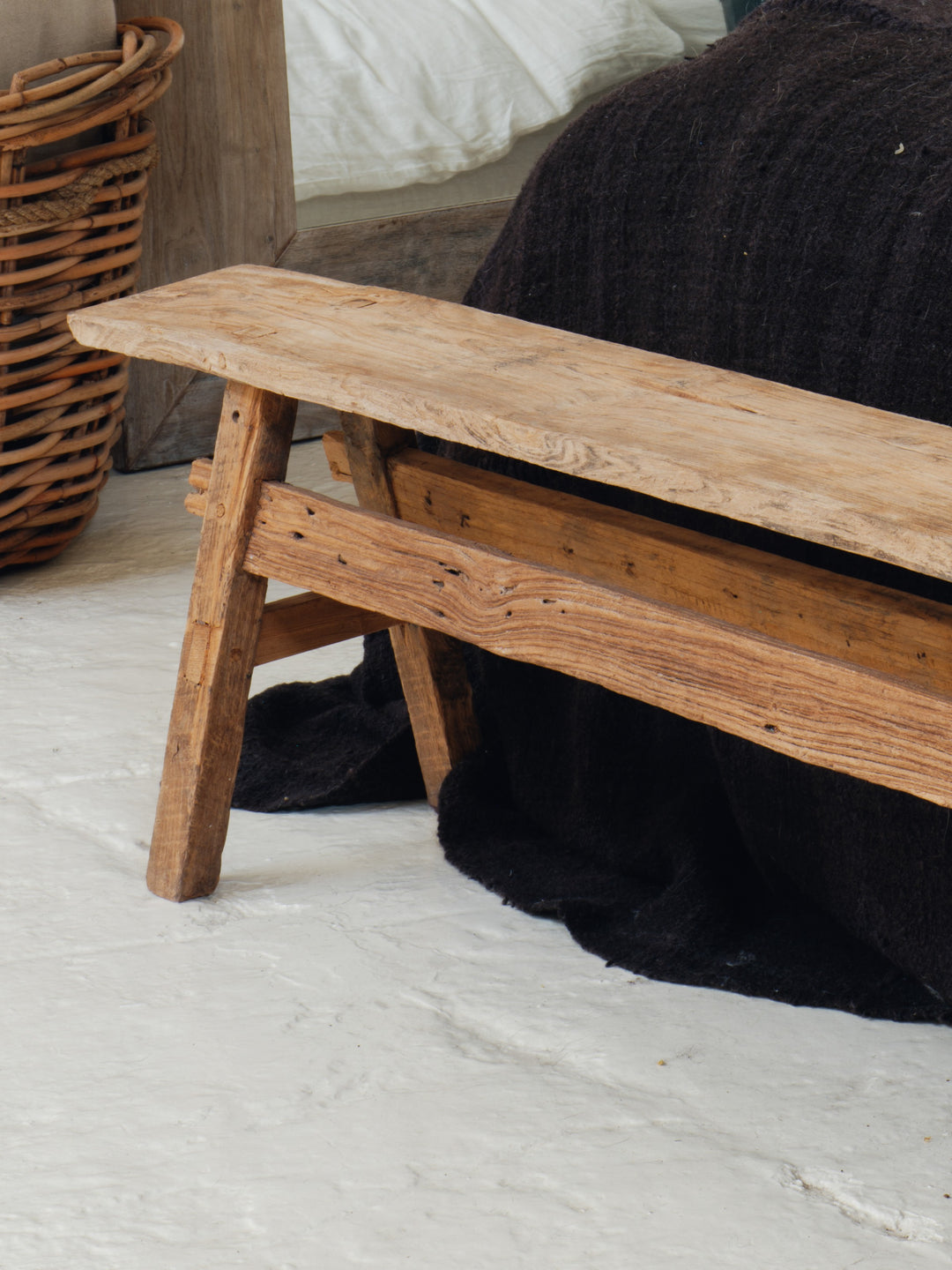 a wooden bench sits on a white floor next to a bed