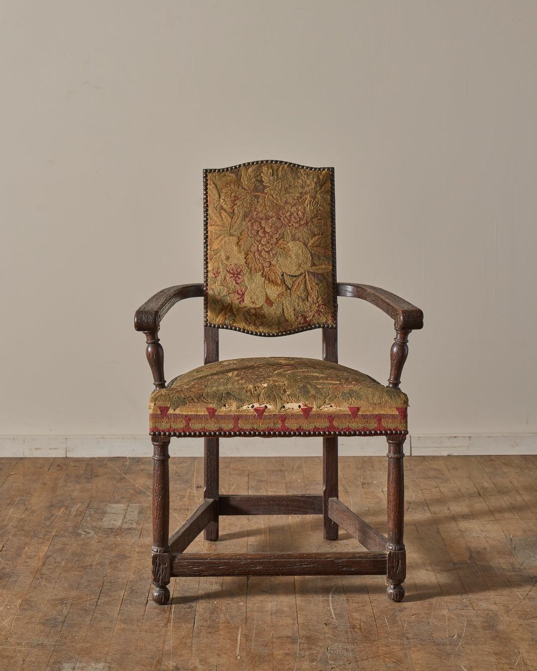 Antique wooden armchair with floral tapestry upholstery.